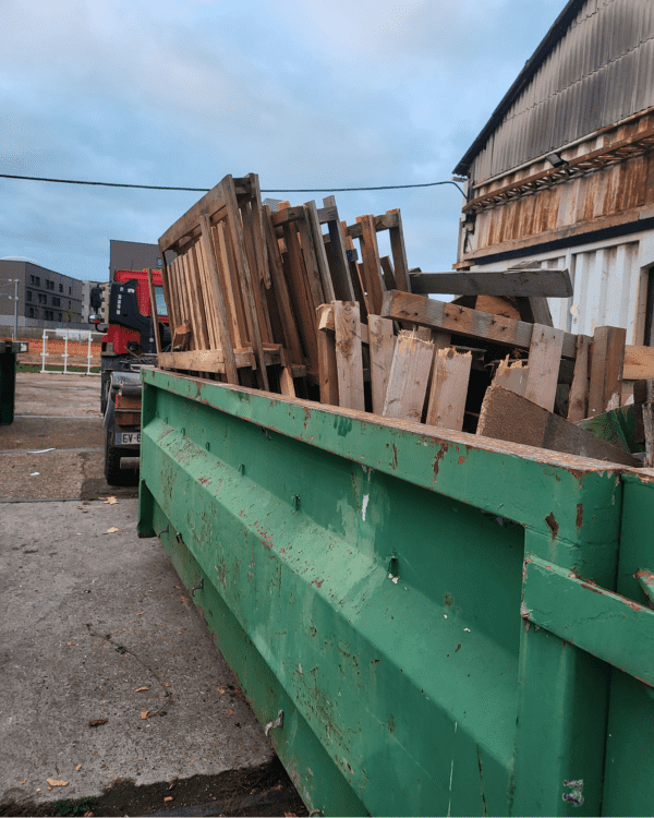 Benne remplie de palettes et de déchets en bois lors d'une prestation de débarras.