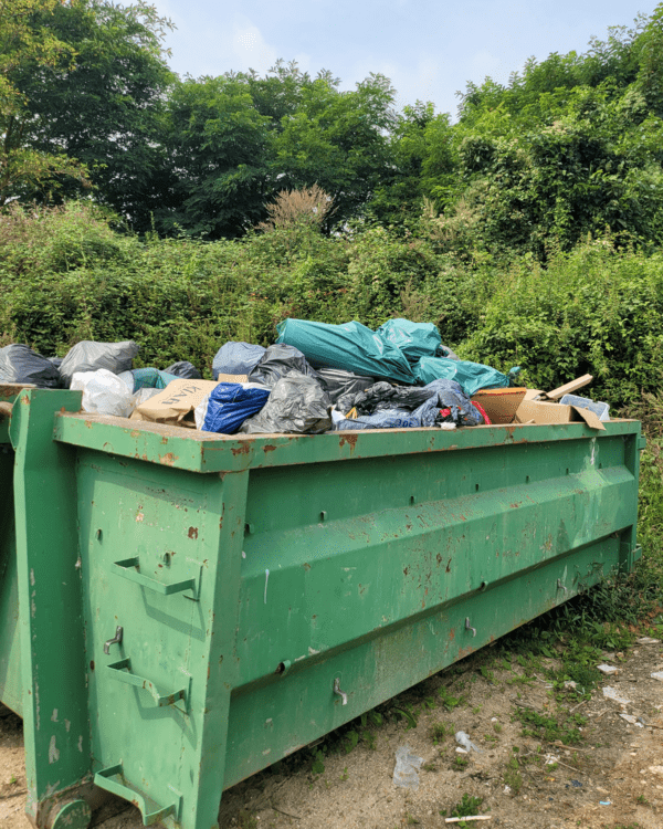 Benne contenant des sacs et des encombrants dans le cadre d'une opération d'évacuation de déchets.