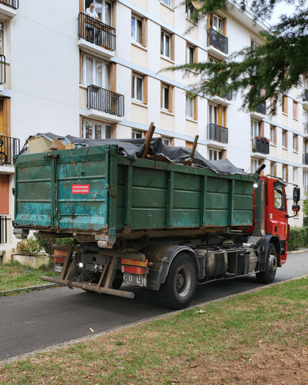 Camion-benne intervenant dans une copropriété pour l'évacuation d'encombrants et de déchets.
