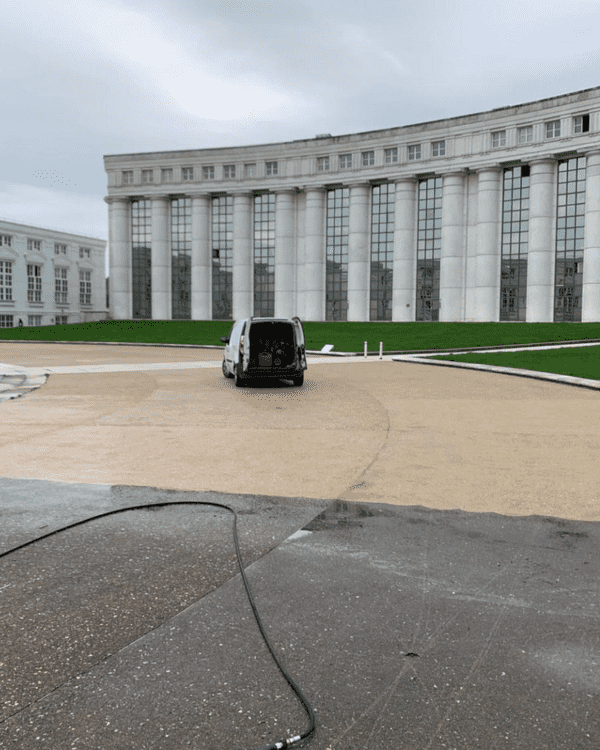 Décapage et nettoyage d'une esplanade située devant un bâtiment professionnel.