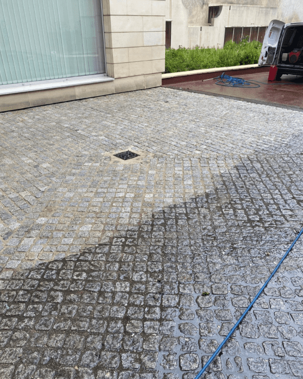 Décapage de pavés extérieurs d'une copropriété avec résultat visible en cours d'intervention.