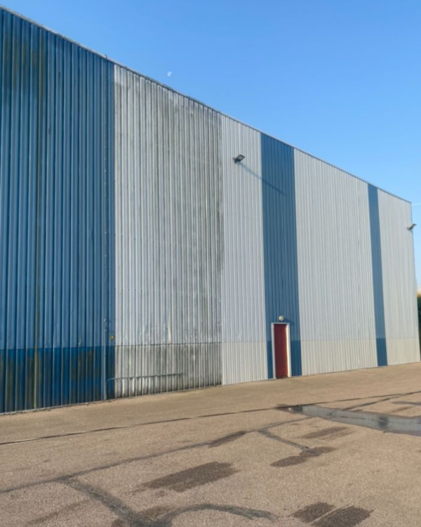 Façade industrielle avant et après nettoyage mettant en évidence le résultat obtenu.