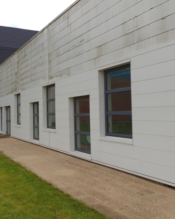 Façade de bâtiment tertiaire en cours d'intervention de nettoyage professionnel.