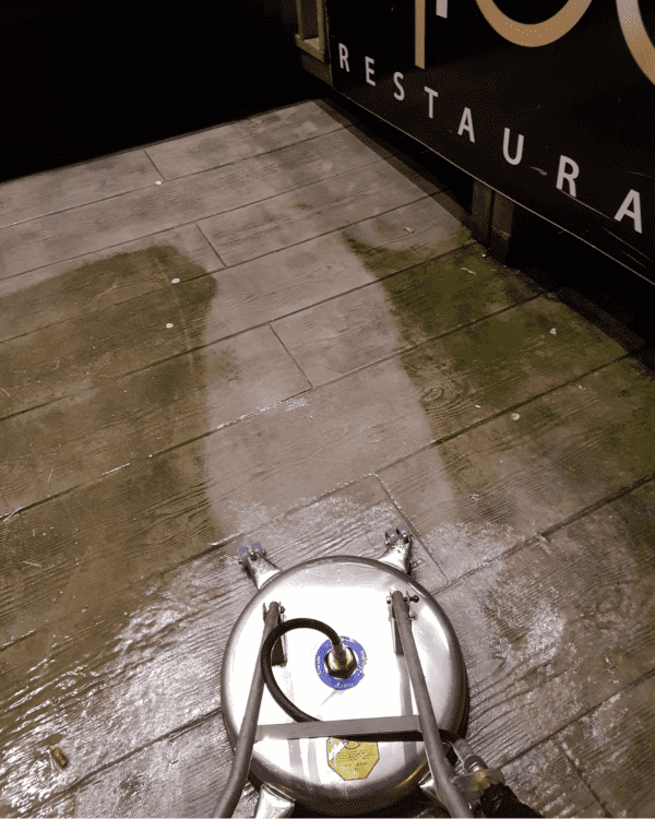 Nettoyage d'une terrasse extérieure à l'aide d'un nettoyeur de surface haute pression.